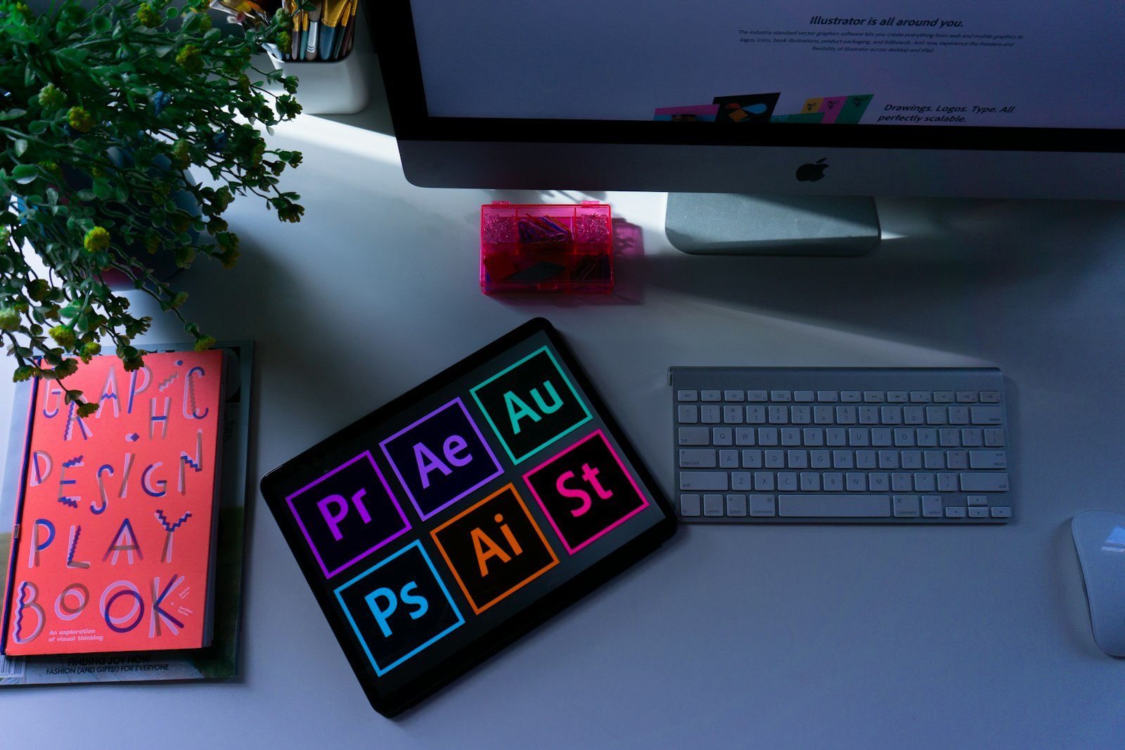 A designer's desk with a graphic design playbook, tablet and creative tools