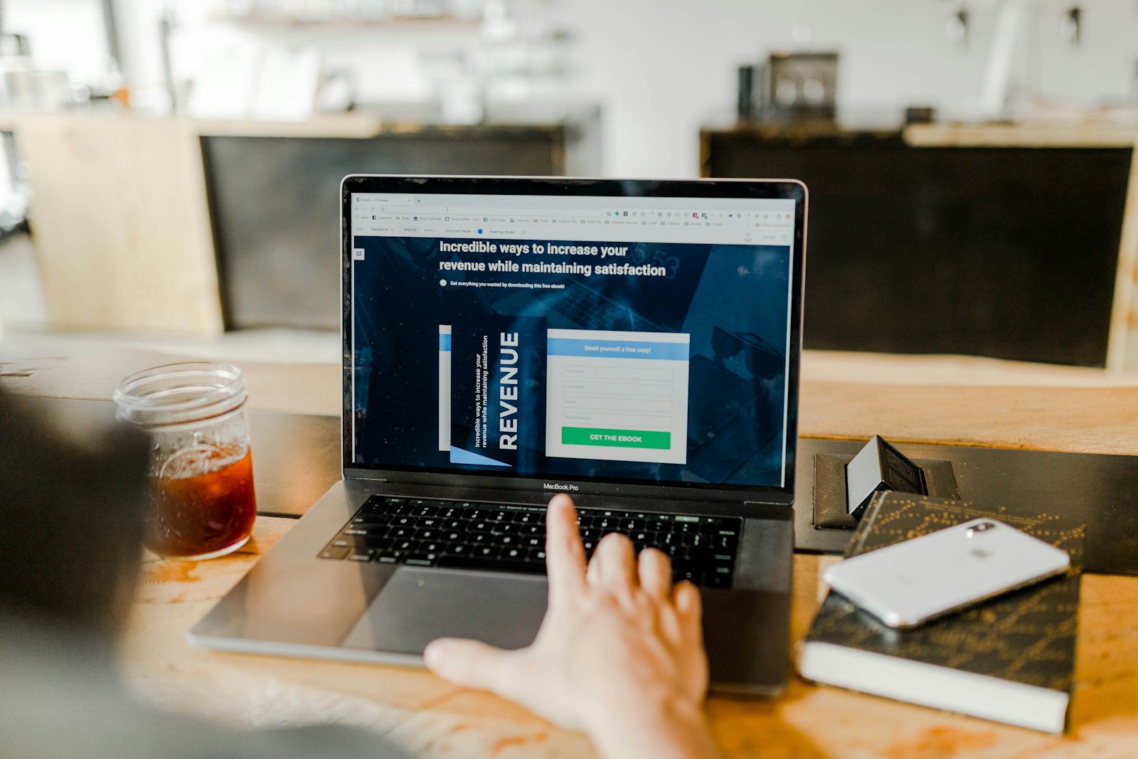 A person viewing a revenue-focused marketing landing page with a lead-capture form on a laptop